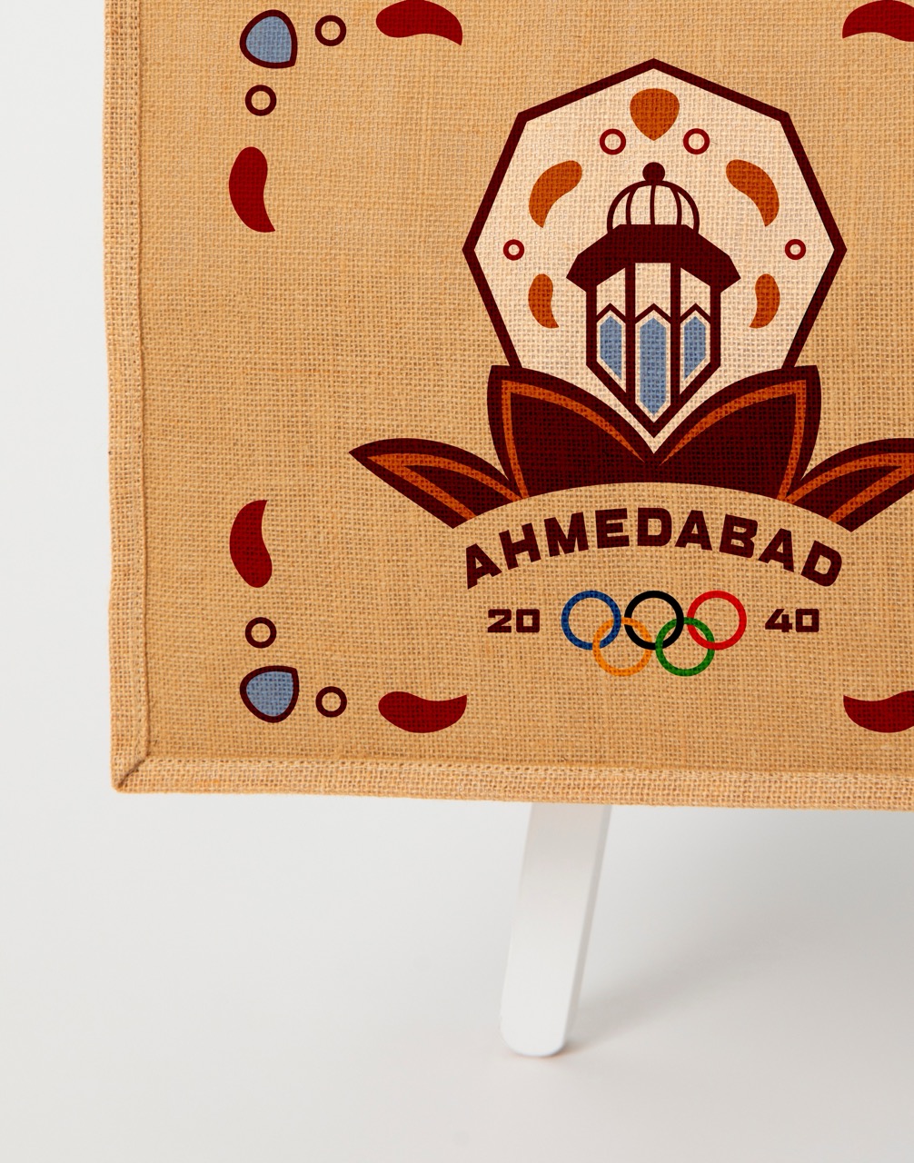 Close up of a mockup of a juke totebag mockup with olympic logo and other decals on a white chair with jeans on the chair.